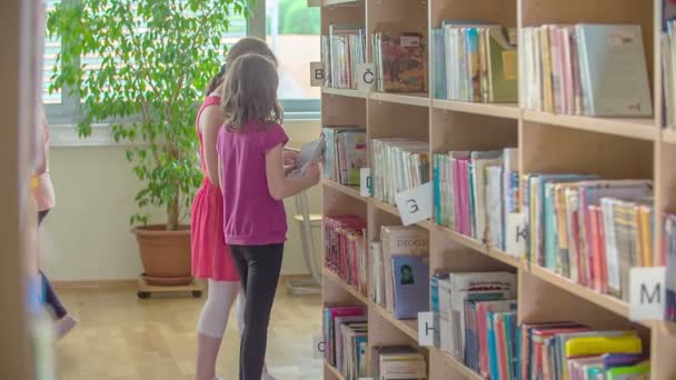 二人の若い学生が本を調べ 図書館の棚に戻す — ストック動画