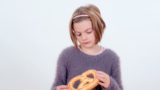 Ein Junges Mädchen Schaut Sich Eine Brezel Und Beißt Dann — Stockvideo