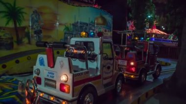 Çocuklar lunaparkta oynuyorlar ve farklı araçlara biniyorlar.