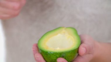 Avokado tohumlarını büyük bir bıçakla çıkarıyorsun. Genç bir kadın küçük bir kaşıkla avokado yemeye başlar.