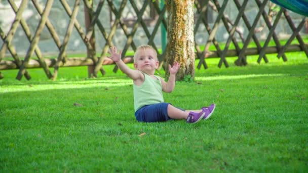 Schattig Baby Meisje Zitten Het Gazon Proberen Iets Grijpen Een — Stockvideo