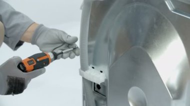 Vidaları pilli matkapla sökmek. Vidalar çamaşır makinesinin arka panelini tutar..