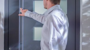 Bir adam düğmeye basAr. Ön kapıyı açtı ve sonra onların içinden geçti..