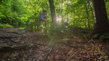Yaşlı oduncu o ağacı kesmekle ilgileniyor. O keskin bir balta taşıyor ve o güzel güneş parlaması geçer.