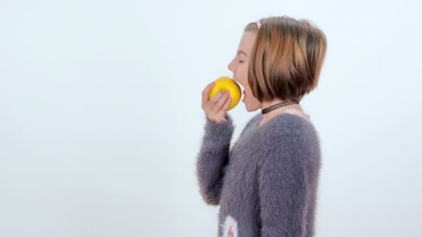 若い女の子は大きな黄色のリンゴにかむされ 彼女は本当にそれが好き — ストック動画