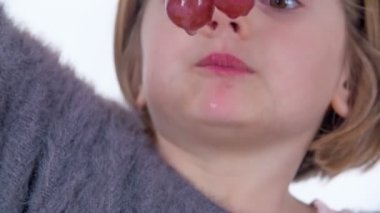 Küçük bir kız alttan büyük kırmızı üzümler yiyor..