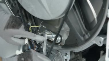 Koruyucu eldiven giyen bir erkek soket anahtarı ile ısıtıcı elementini tutan vidayı söküyor..