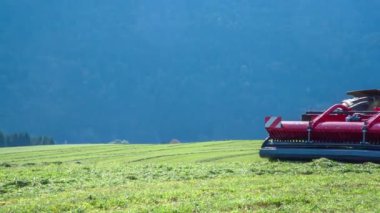Büyük bir traktör önündeki makineyle çim kesiyor..