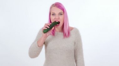 Bir kadın bir salatalığı ısırıyor, çiğniyor ve sonra tükürüyor..