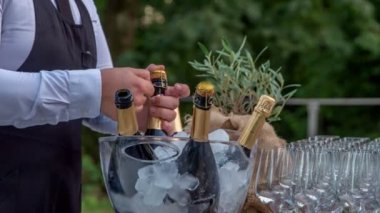 Barmen şampanya şişesinin boynundaki folyo kağıdını soyuyor.