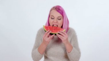 Genç bir kadın bir dilim karpuz ısırıyor..