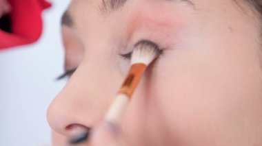 Makyöz yavaş yavaş müşterinin göz kapağını kaldırır ve müşterinin göz kapağına daha koyu bir renk uygular..