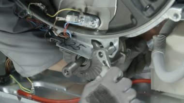 Tamirci, çamaşır makinesinin özel bir parçasını çıkarmak için çok uzun bir vidayı dikkatlice söktü..