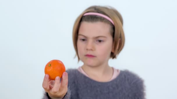 Une Jeune Fille Observe Une Petite Mandarine Dans Main — Video