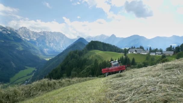 トラクターが丘の真ん中に立っていて 後ろには素晴らしい景色があります 農家は夏に干し草を準備しています — ストック動画