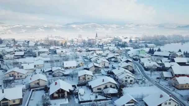 雪の村の美しい一日 背景には教会もあります その景色はおとぎ話のように見える 航空写真 — ストック動画