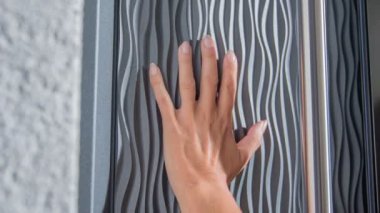 Bir kadın çok modern bir ön kapıya eliyle dokunuyor..