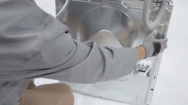 Yıkama makinesinin iç parçaları görünür ve erişilebilir olsun diye metal tahtayı kaldıran adam..