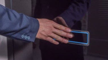 Giriş kapısının önünde bir adam duruyor. Onlara dokunuyor, sonra bir şeye basıyor ve kapı açılıyor..