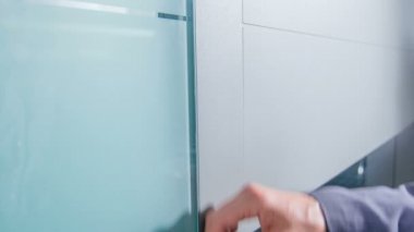 Bir adam kapının önünde duruyor ve o yavaşça eliyle ön kapıya dokunuyor.