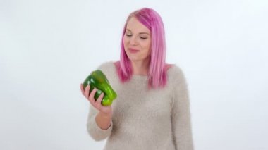 Genç bir kadın büyük bir yeşil biber içine ısırır.