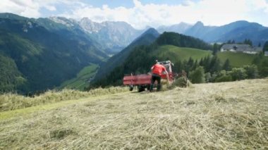 Bazı saman römork tekerleğinde sıkışmış ve bir çiftçi onu çıkarıyor. Arkadaki manzara inanılmaz..