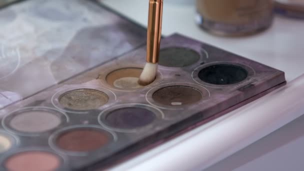 化妆师把画笔浸入眼底调色板上的浅褐色眼罩中 — 图库视频影像