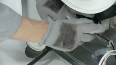 Tecrübeli bir tamirci su giderinin hortumunu nazikçe çekiyor. Bozuk çamaşır makinesini tamir ediyor..