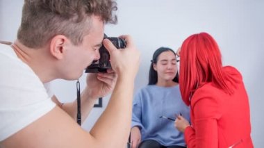 Makyaj sanatçısı modelin kaşlarını şekillendirdiğinde, bir fotoğrafçı onların fotoğraflarını çeker.