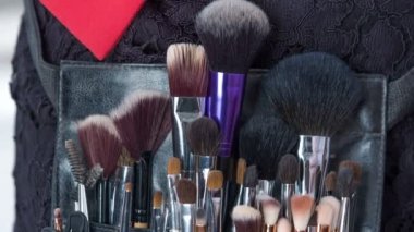 Makyaj sanatçısı fırça setinden fırçasını alır ve müşterinin göz kapaklarına bir sonraki göz farı takmak için kullanır..