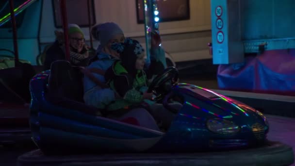 若いお母さんと彼女の小さな息子楽しみます運転とともにAバンパー車寒い冬の夜遅く — ストック動画