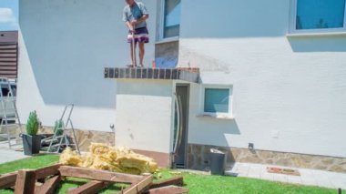 Yaşlı adam çatıdaki çöpleri temizlerken genç adam dinleniyor ve devam etmek için tüm gücü topluyor..