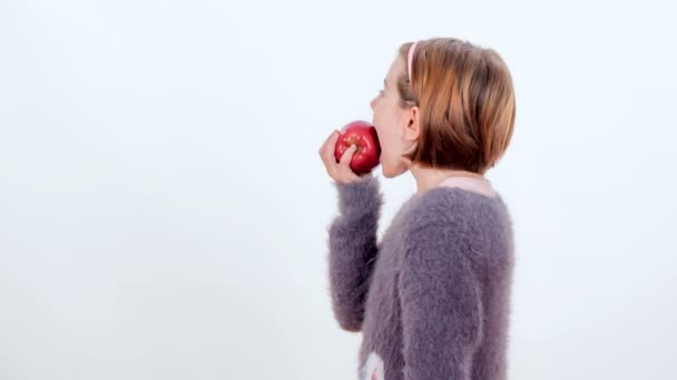 一个年轻女孩正在咬着一个美味的红苹果 — 图库视频影像