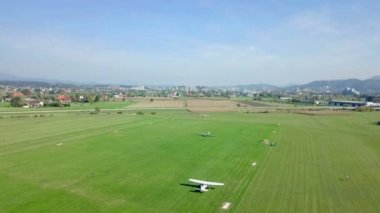 Küçük beyaz uçaklar bu küçük havaalanına iniyor. Büyük bir yeşil çim alanı var. Havadan çekim.