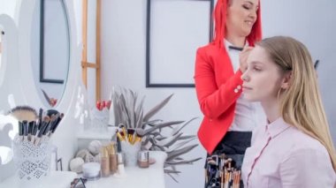 Bir makyaj sanatçısı terbiye tozu için büyük bir fırça kullanır ve müşterinin çeneve ağzına uygulayarak.