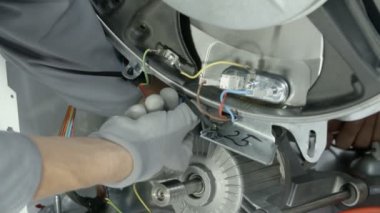 Deneyimli tamirci, çamaşır makinesinin özel bir parçasını çıkarmak için çok uzun bir vidayı dikkatlice söktü..