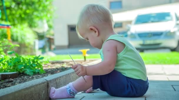 美丽而好奇的幼儿坐在花园里 在炎热的一天玩蔬菜标签 — 图库视频影像