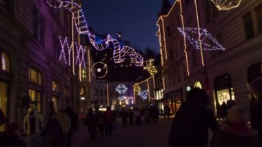Küçük çocuklu aileler, Slovenya 'nın Ljubljana kentinde sihirli bir şekilde dekore edilmiş caddede yürümekten keyif alıyorlar..