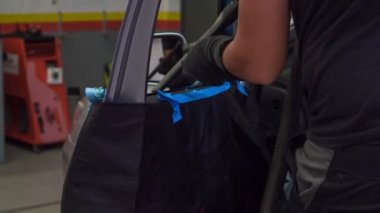 Bir tamirci arabanın kapısını tamir ediyor ve kırık bir bardağı yenisiyle değiştirecek..