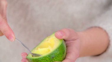 Kadın lezzetli ve taze avokadoyu yemek kaşığıyla kaşıklıyor.
