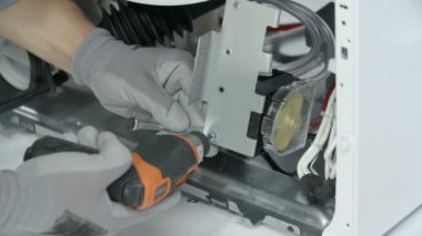 Tamirci, küçük bir batarya matkabıyla elektrik panelini söküyor..