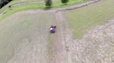 Tepede saman hazırlayan büyük bir traktörü izlemek. Hava görüntüsü. Burası çok dik, dağların tepesinde bir yer..