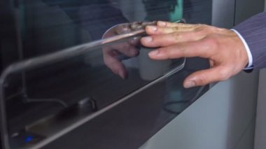 Bir işadamı önce ön kapıya dokunur. Sonra kapıyı açmak için bir düğmeye basıyor ve içeri giriyor..