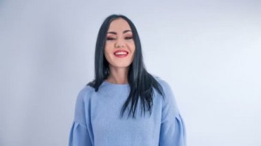 A young woman has a fresh make up on. She claps and then she gives thumbs up.