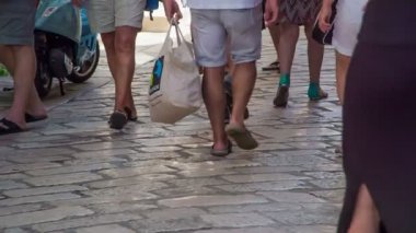 Turistler şort giyiyorlar ve kaygan ayakkabılar giyiyorlar.