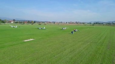 Küçük uçaklardan biri az önce indi. Hava güzel ve güneşli. Birkaç kişi podyumda duruyor. Hava görüntüsü.