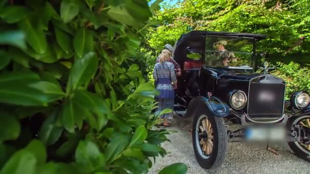 一辆老式汽车正站在一条小路上 一对年轻夫妇正上车 周围的自然是美丽和绿色的 — 图库视频影像