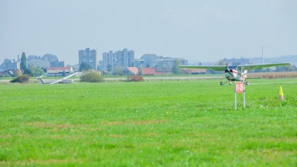 Малий Спортивний Літак Приземляється Зелену Траву Сонячний День Житловим Районом — стокове відео