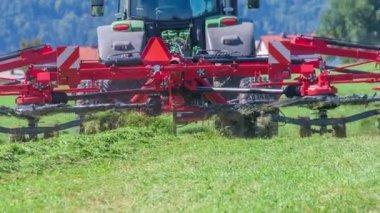 Çiftçiler sabahın erken saatlerinden itibaren çalışıyor ve büyük bir çim tarlada ot kesiyorlar..