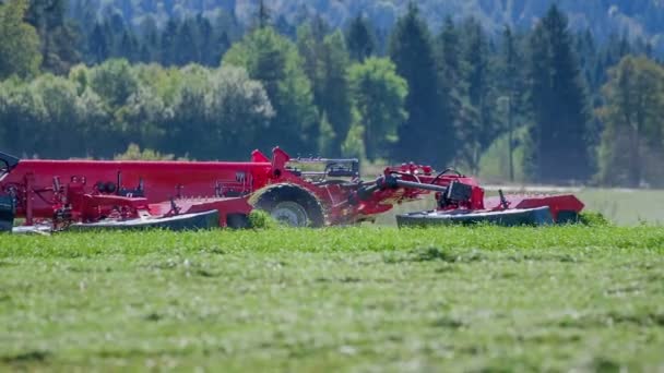 農夫がトラクターを運転し 彼の後ろに農業機械を引っ張っています 農民は草を刈っている — ストック動画